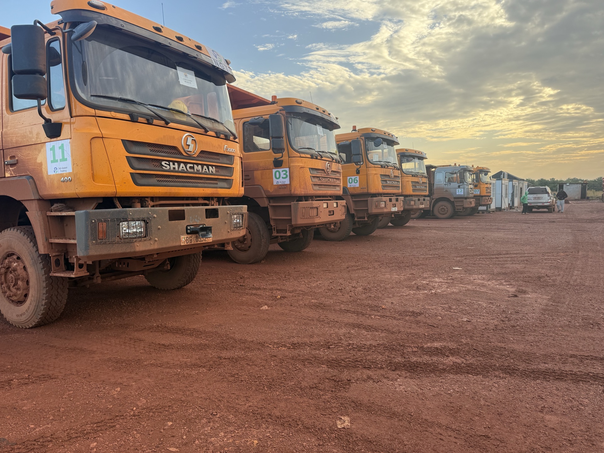 Two dump trucks parked under a maintenance canopy