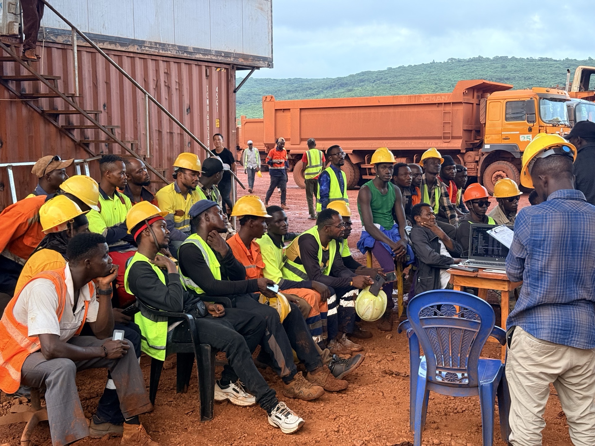 Workers seated for a night training session near shipping containers